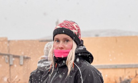 Ung jente inn i reingjerde med reinsdyr rundt seg.